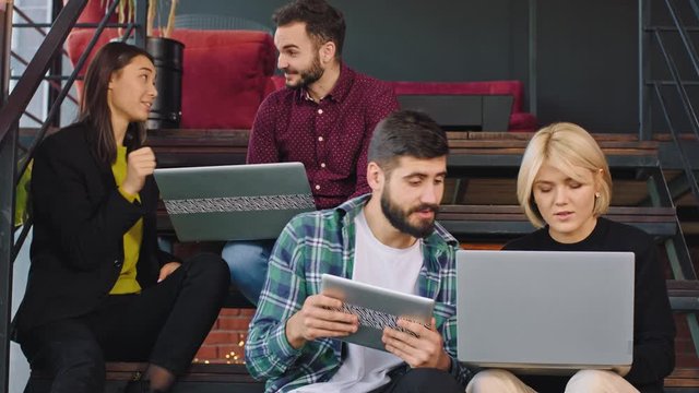 attractive young group of students while have a break time on the college stairs analyzing the homework using the tablet and notebook