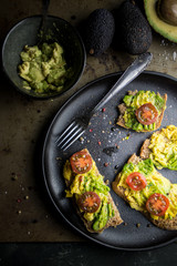 Avocado toast with tomatoes in a black plate