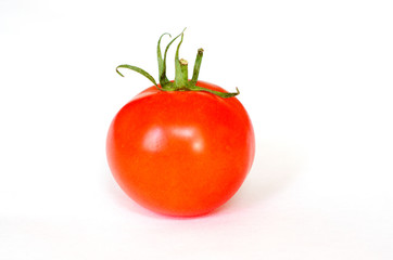 One fresh red tomato lie on a white background. Selective focus. Close up.