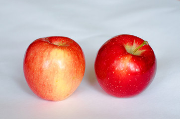 Two fresh red apples lie on a white background. Selective focus. Close up.