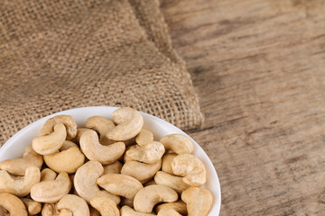 Cashew nuts in a white bowl on the table. Healthy food.