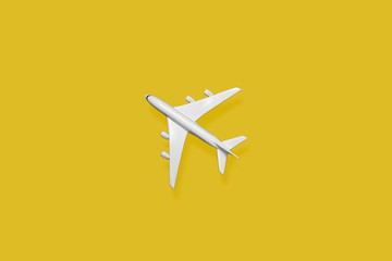 Fototapeta premium Flat lay of miniature toy airplane on yellow background
