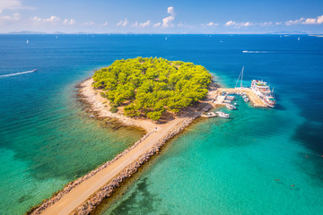 Obraz na płótnie Canvas Aerial view of beutiful small island in sea bay at sunny bright day in summer in Murter, Croatia. Top view of transparent blue water, green trees, sandy beach, boats and yachts. Tropical landscape