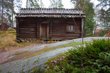 Fototapeta na wymiar Ancient authentic wooden house of the 17th century in a forest on the island of Seurasaari in Helsinki, Finland, a cloudy day in late autumn.