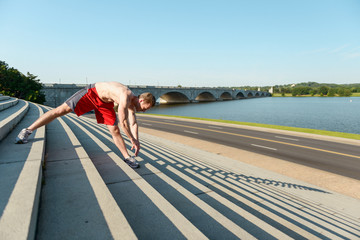 Fit caucasian man stretching on steps during an intense outdoor workout in the early morning in Washington DC - 313157157