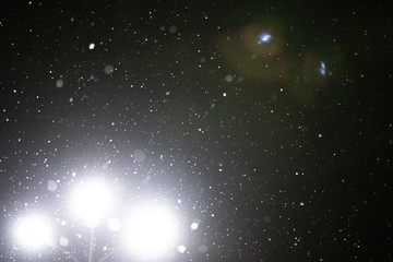 Obraz premium Snow and bokeh in the light of a lantern on a black background