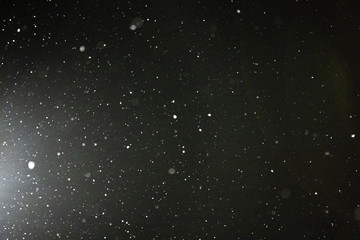 Snow and bokeh in the light of a lantern on a black background