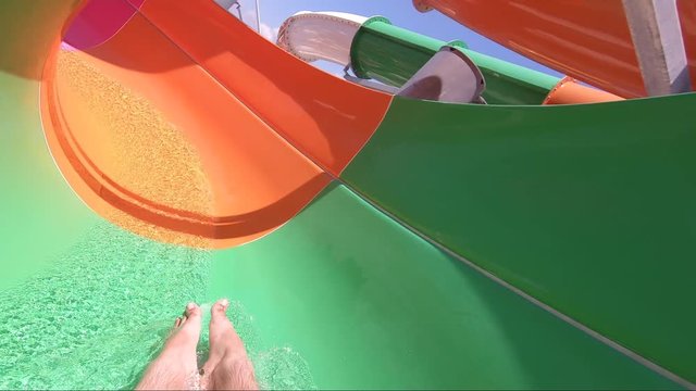 Man having fun on a water slide. Cool people having fun on the water slide in the aqua fun park glides playing happy and water splashes are all over.