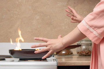 Shocked woman and fire on frying pan on home kitchen concept.