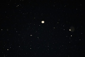 Snow and bokeh in the light of a lantern on a black background