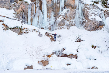 Fototapeta na wymiar man walks on frozen lake Braies in Italy in winter, concept of winter travel