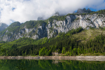 rock face with clouds over lake gosau