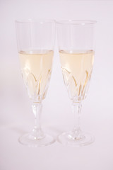 Copas de cristal con vino blanco sobre fondo blanco.