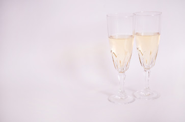 Copas de cristal con vino blanco sobre fondo blanco.