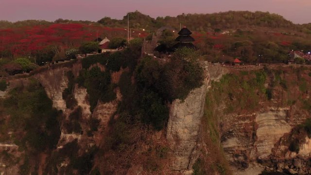 Aerial drone flight over Pura Luhur Uluwatu temple at pink evening, Bali, Indonesia, 4k