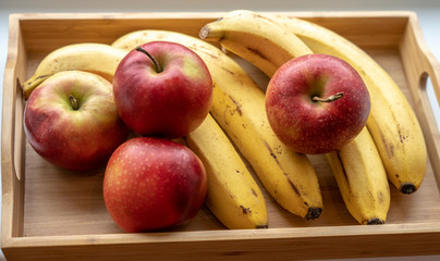 a wooden fruit tray with ripe bananas and apples on it