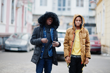 Two african male friends walking together, wear on jackets with hoodie.