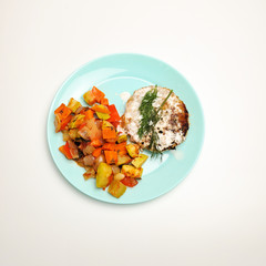 Roast Turkey cutlets on the grill, fry vegetables on a plate. Steam cutlets with boiled vegetables. stewed cutlets and stewed vegetables, healthy food.