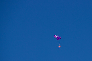 Against the blue sky, purple balloons and a red heart. St. Valentine's Day.
