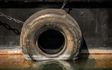 Hanging by a chain, an old tire acts as a boat bumper.