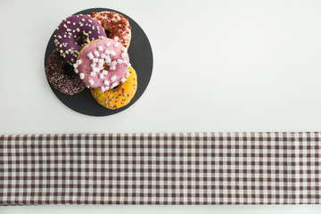Doughnuts of various flavors with shavings on white surface with checkered cloth. Snack concept.