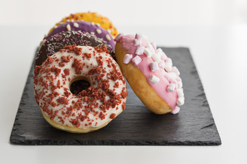 Donuts of various flavors with shavings on slate surface. Snack concept.