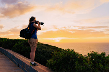 Sunrise or sunset and young girl with camera at Capo Ferro in at Mediterranean sea in Sardinia...