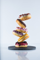 Plate of doughnuts or donuts of various colors and flavors on a white surface