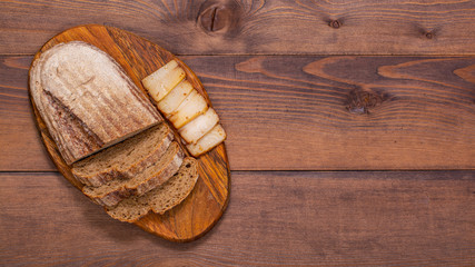 Smoked lard with bread on wooden background