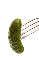 Pickled cucumber sticking on a fork isolated on white