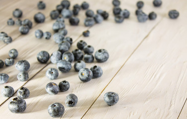 Black blueberries scattered on a white wooden table