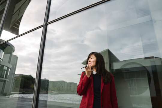 Businesswoman standing near to modern building and using smartphone