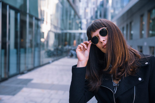 Portrait of women with sun glasses looking at camera, hand on glasses