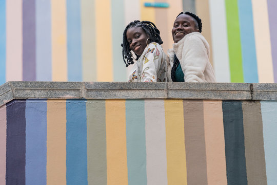 Portrait of smiling friends leaning on wall