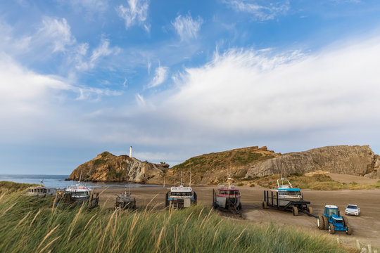 Ships at the beach with lighthouse in the back, Castlepoint, New Zealand