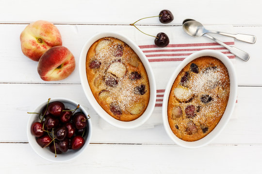 Bowls of gluten free homemade clafoutis with cherries, peaches and almonds