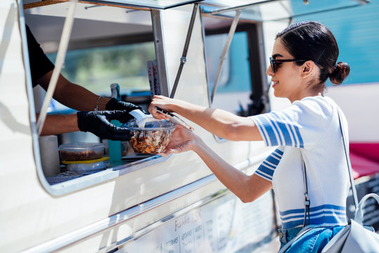 Young woman buying take away food from a street food stand