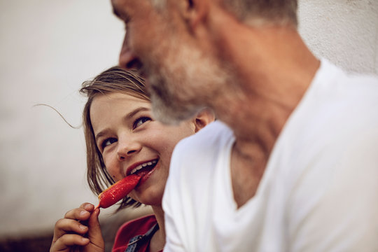 Portrait of smiling girl with popsicle looking at her father