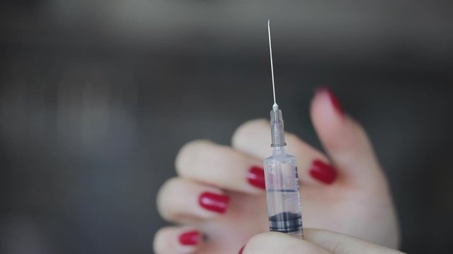 Girl squeezes some of the liquid from the syringe to release the air and getting ready to give an injection