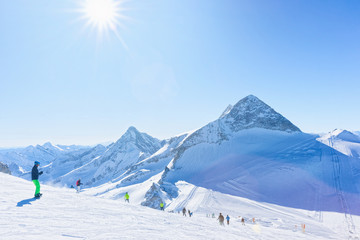 Men Skiers and snowboarders on Hintertux Glacier in Tyrol in Mayrhofen of Austria, winter Alps. People with Ski and snowboard at Hintertuxer Gletscher in Alpine mountains. Sun shining.