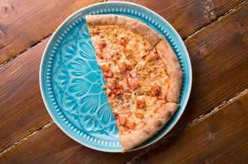 Pizza margarita with tomato and  mozzarella cheese. served at beautiful blue dish on wooden table. flat lay