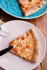 Pizza margarita with tomato and  mozzarella cheese. served at beautiful blue dish on wooden table. close up. flat lay