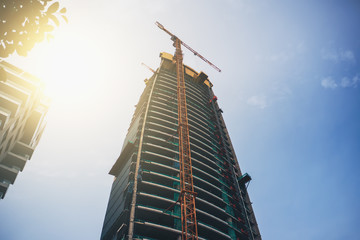 New Skyscraper Construction with Industrial Crane at sunny sky background.