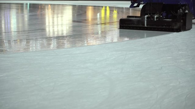 The ice rink cleaner updates the surface of the ice rink in the evening. Close-up. Winter activities and hobbies