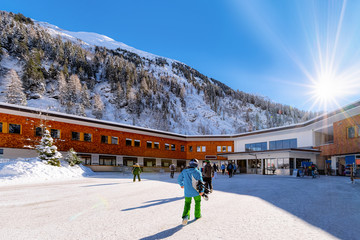 Snowboarder and Skiers going to cable car station in Hintertux Glacier in Tyrol in Mayrhofen in Austria, winter Alps. People at ticket pass building in Hintertuxer Gletscher in mountains. Sun shining