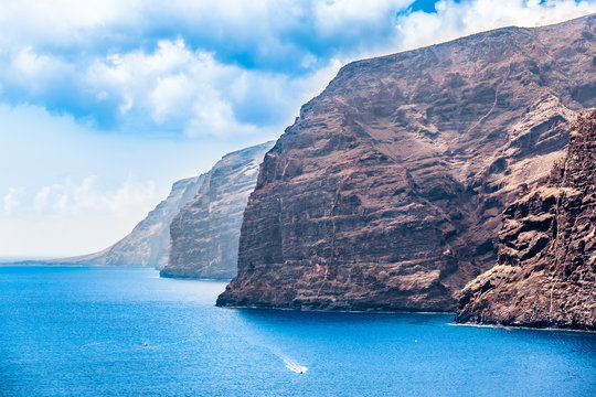 Los Gigantes Rocks / Huge rocky cliff at coast of Atlantic ocean on Tenerife island with small boats (copy space)