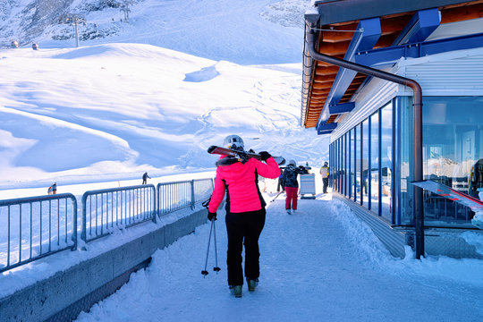 Woman Skier with ski going to cable car station in Hintertux Glacier in Tyrol in Mayrhofen in Austria, winter Alps. Lady girl at ticket pass building in Hintertuxer Gletscher in Alpine mountains