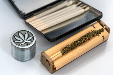 Hands making Marijuana joint from cigarette rolling machine, paper.