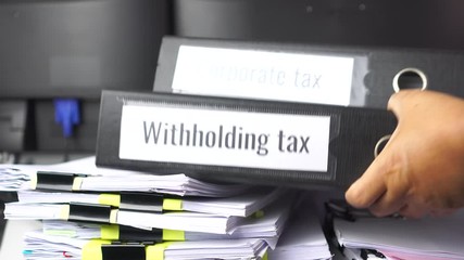 Stack of taxes binders report concept: Document of Withholding tax and corporate tax for accountant. withholding tax sometimes applies to royalties, rent or even sale duty must be paid to government