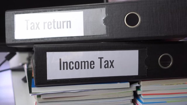Tax return and Income tax files binder of report, document in office. completion of documentation that calculates entity&rsquo;s income earned  of payable to government, organisations or potential taxpayers